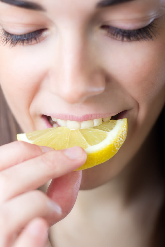 Держит еду во рту. Человек ест лимон. Девушка ест лимон. Девушка с лимоном. Человек ест кислое.